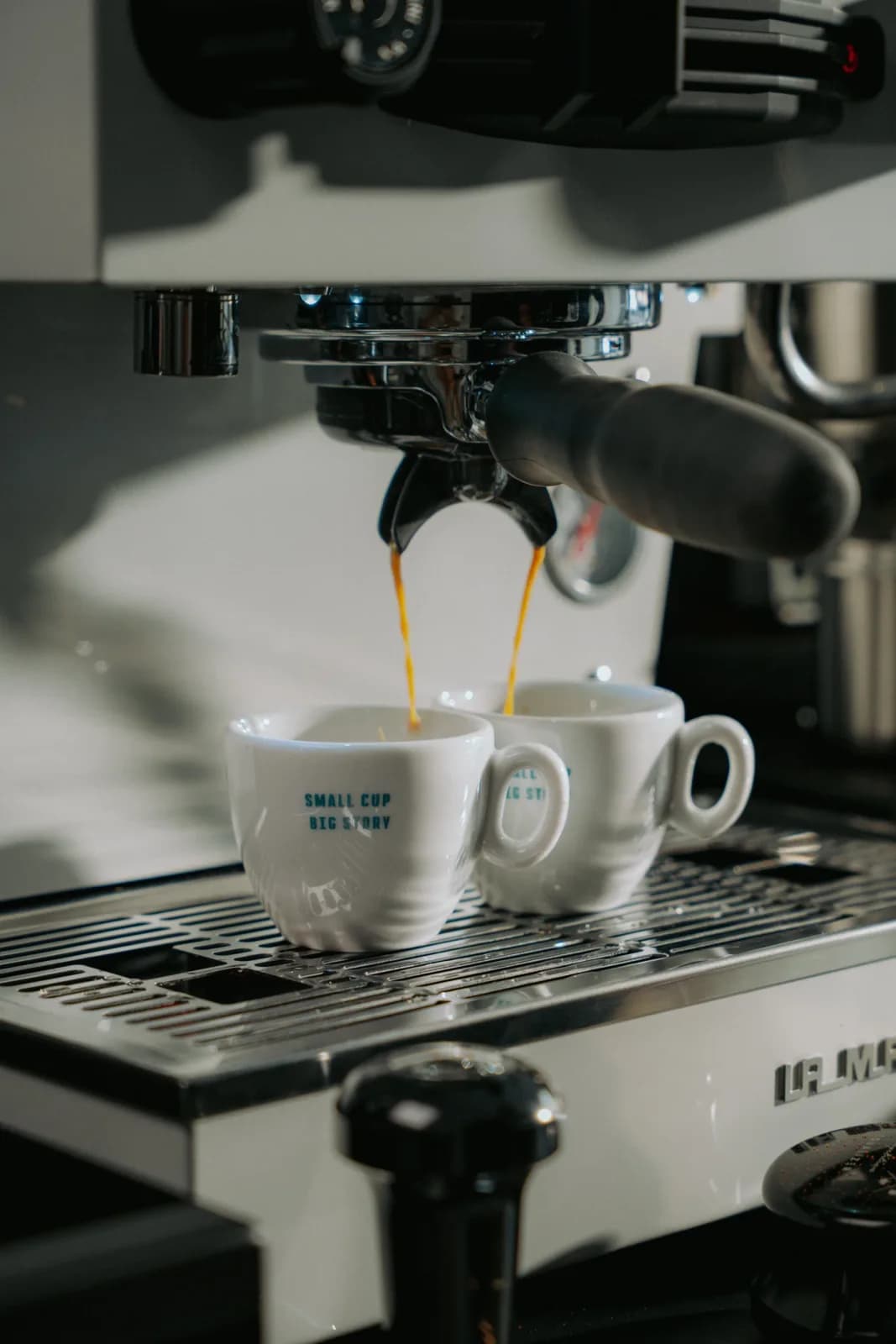 Doppelter Espresso läuft aus dem Siebträger in zwei Tassen